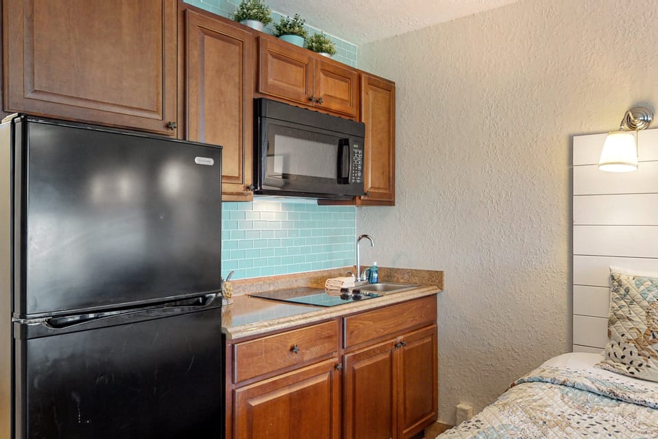Well-equipped beach-inspired kitchenette with fridge, cooktop, sink, and microwave. Perfect for an easy beach stay, offering convenient meal prep and cozy coastal charm just steps from the ocean.