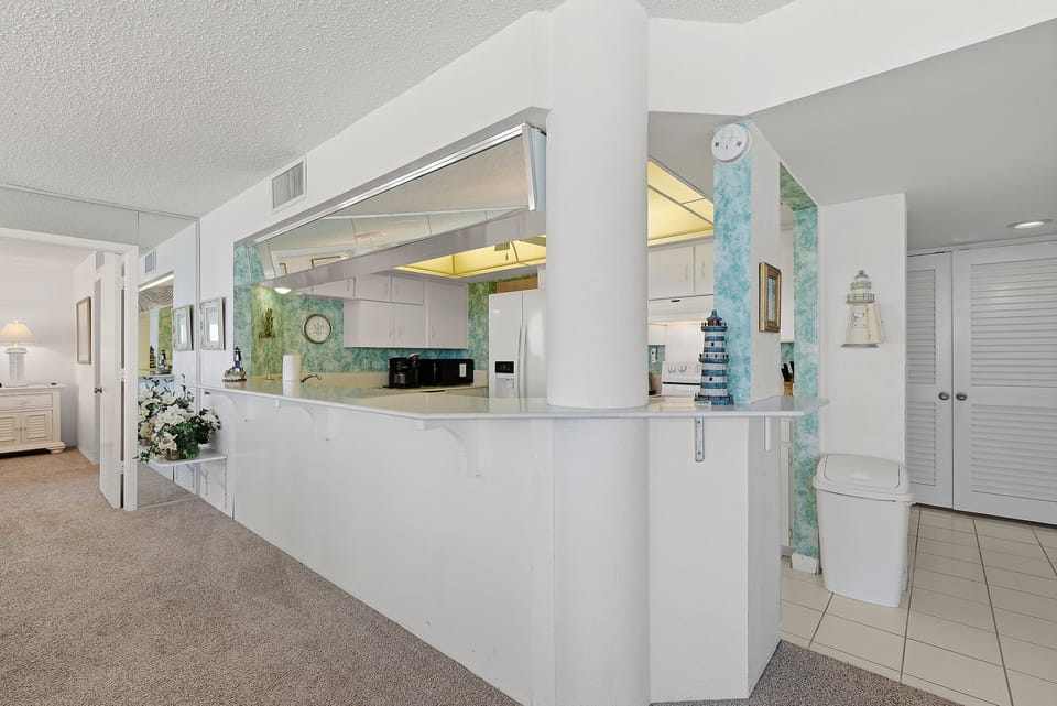 This bright, open kitchen features coastal accents and a convenient breakfast bar, perfect for easy meals during your beach stay. Enjoy a functional layout that keeps you connected to the living space after a day by the ocean.