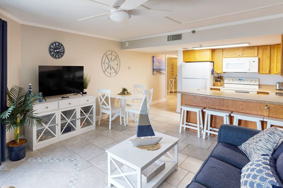 Enjoy a relaxing beach stay in this open-concept living and dining space featuring coastal décor, comfortable seating, and a fully equipped kitchen. Perfect for gathering after a day at the beach.