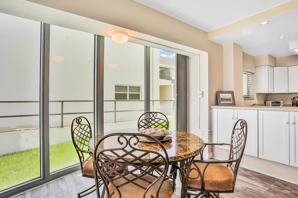 Bright dining nook with large windows and elegant seating, perfect for enjoying meals between beach adventures. A relaxing spot to unwind during your coastal stay.