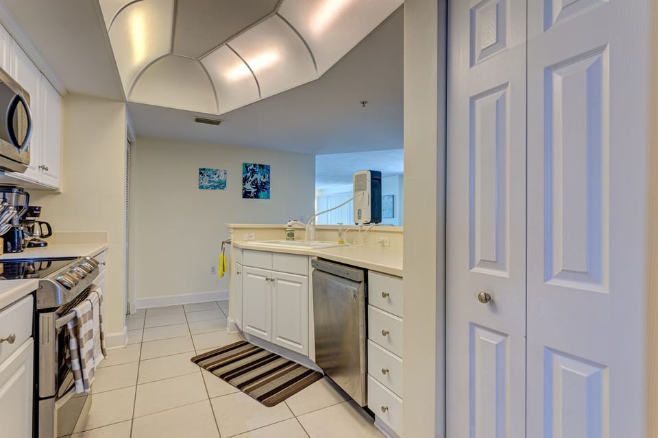 Bright coastal kitchen with modern appliances and a convenient breakfast bar, perfect for casual meals during relaxing beach stays. Enjoy easy living and quick bites before heading to the shore.