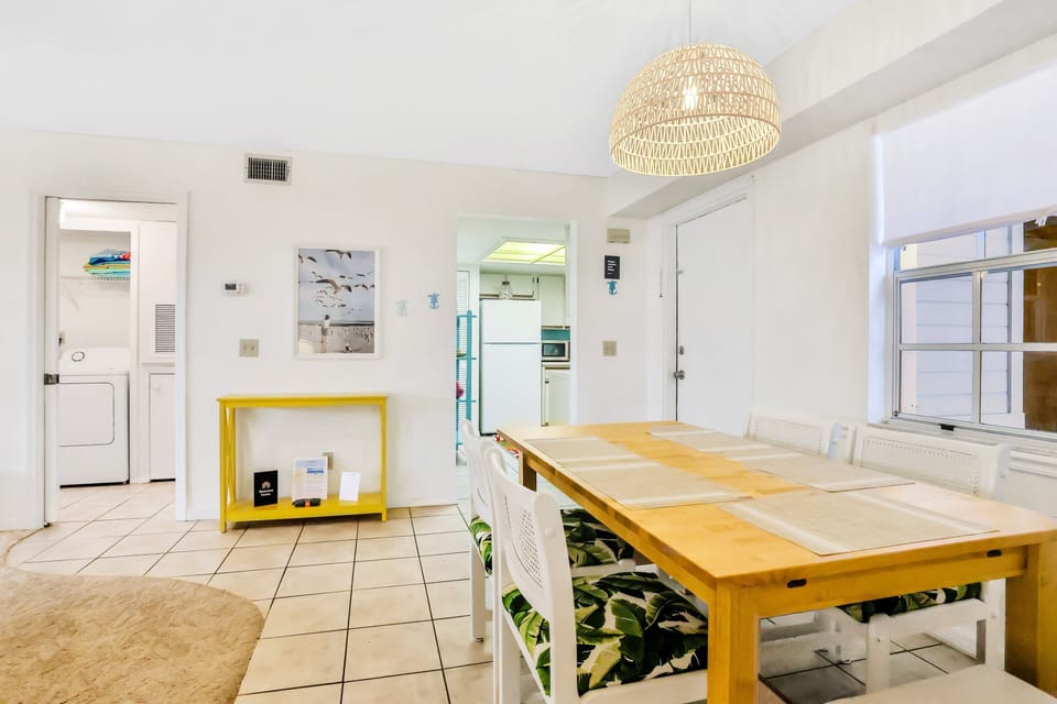 Gather around the bright dining table for family meals and game nights during your beach stay. This open, coastal-inspired space connects seamlessly to the kitchen and living area, perfect for relaxing after a day of sun and sand.