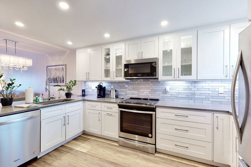 Cook with ease in this bright, fully equipped coastal kitchen featuring stainless steel appliances and ample space. Ideal for fueling your beach stay with home-cooked meals after a day by the ocean.