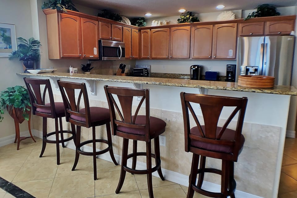 Start your day at the spacious kitchen bar with comfortable seating and coastal charm. Perfect for a relaxed beach stay, this inviting space is ideal for quick breakfasts, snacks, and gathering after a day by the shore.