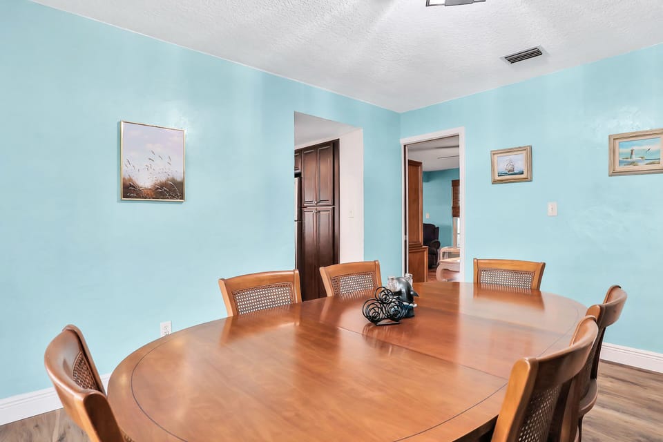 Gather around the table during your beach stay in this spacious dining room with coastal tones and comfortable seating—perfect for family meals, game nights, and planning your next day by the beach.