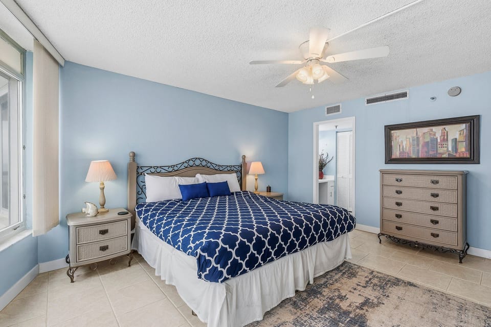 Calming king bedroom with coastal colors, plush bedding, and soft lighting. Designed for comfort and relaxation, it's the perfect retreat to unwind and recharge during your memorable beach stay.