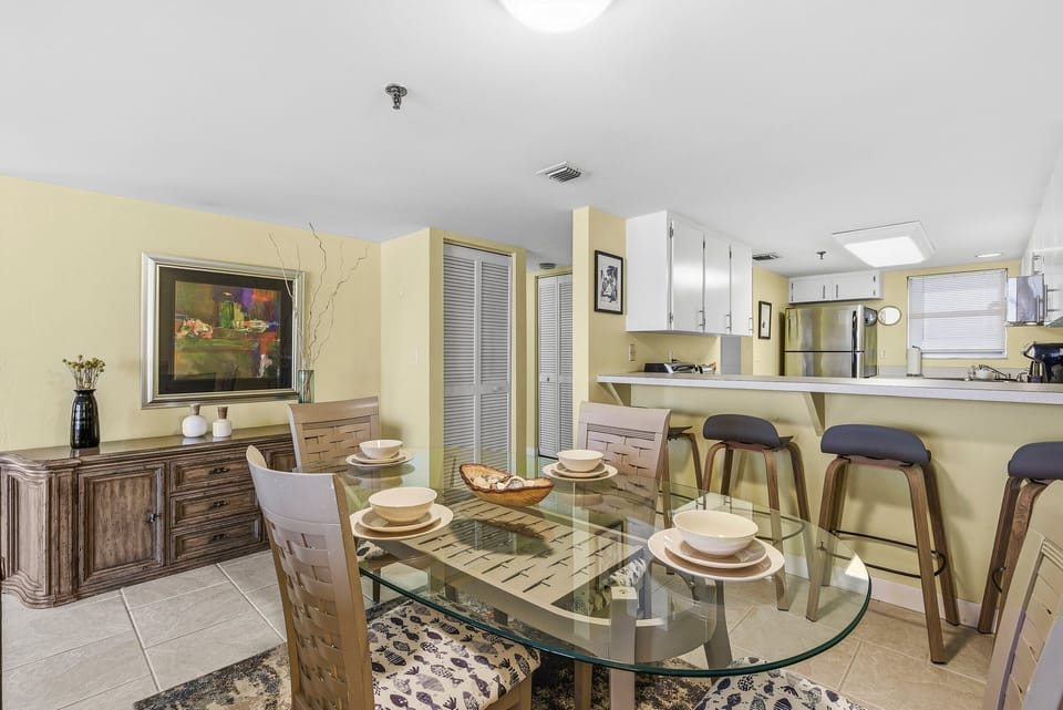 Stylish dining area with seating for meals and a convenient kitchen bar. Perfect for gathering with family or friends and enjoying relaxed meals during your comfortable beach stay.