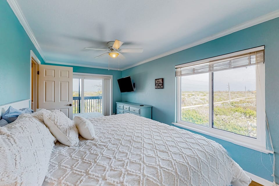 Bright beachside bedroom with a plush king bed, balcony access, and expansive dune views. Soft coastal hues and natural light create a peaceful retreat for your perfect beach stay.