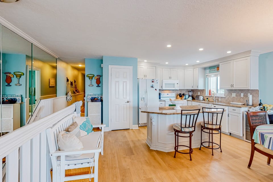 Spacious coastal kitchen and seating area perfect for your beach stay. Enjoy bright décor, ample counter space, and easy flow to living areas—ideal for relaxing after a day on the sand.
