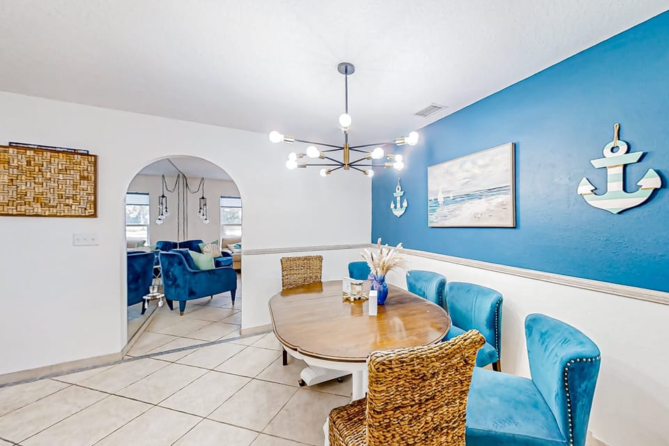 Enjoy meals in this bright, beach-inspired dining room featuring nautical décor, comfy seating, and a modern chandelier—an inviting space to gather during your beach stay.