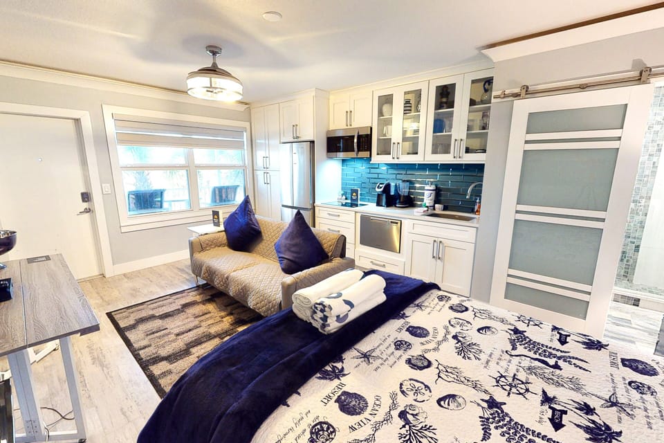 Enjoy this comfortable beach stay studio featuring a cozy bed, modern kitchenette, and inviting seating area. Coastal décor and bright design create the perfect space for a relaxing seaside escape.