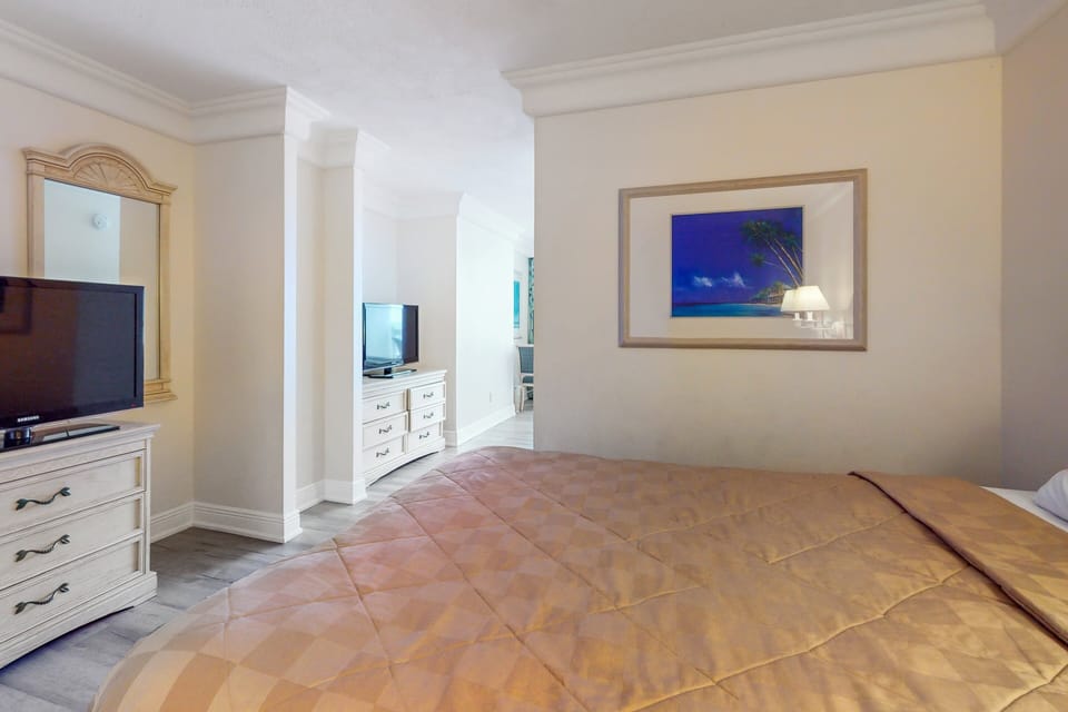 Relax in this comfortable beachside bedroom featuring a plush bed, flat-screen TV, and soothing coastal décor. A perfect retreat after a fun-filled day on the shore.