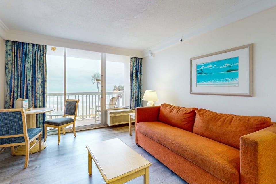 Bright beachside living room featuring a comfy sofa, dining nook, and sliding doors that open to ocean views—perfect for unwinding after a day on the sand.