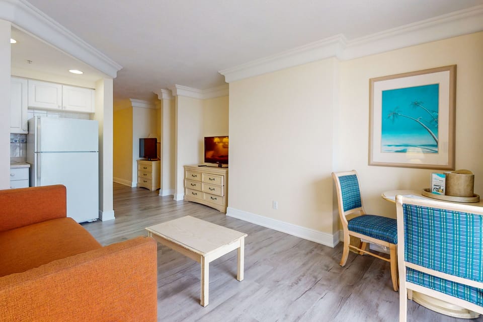 Inviting beach-stay living space featuring comfy seating, dining area, and light coastal décor. Relax after a day on the sand in this spacious, sunlit retreat.