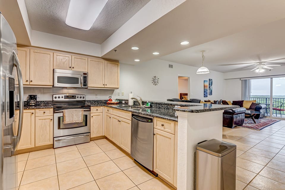 This open, fully equipped kitchen features stainless steel appliances and generous counter space. Ideal for your beach stay, it flows into the living area—perfect for preparing meals after a day by the ocean.
