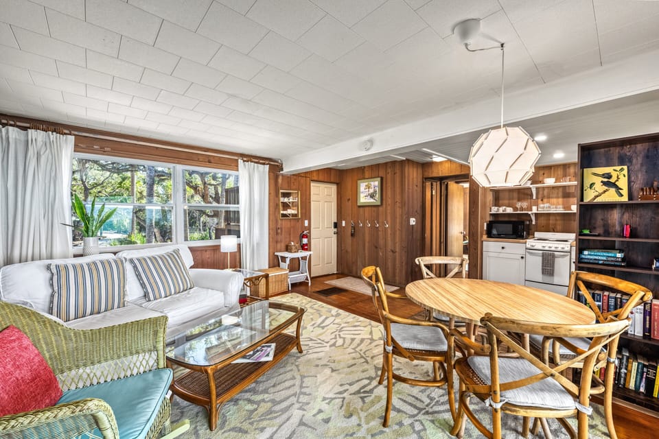 Soft sunlight fills the living area, highlighting cozy seating and a relaxed, airy atmosphere with Gulf light streaming in.