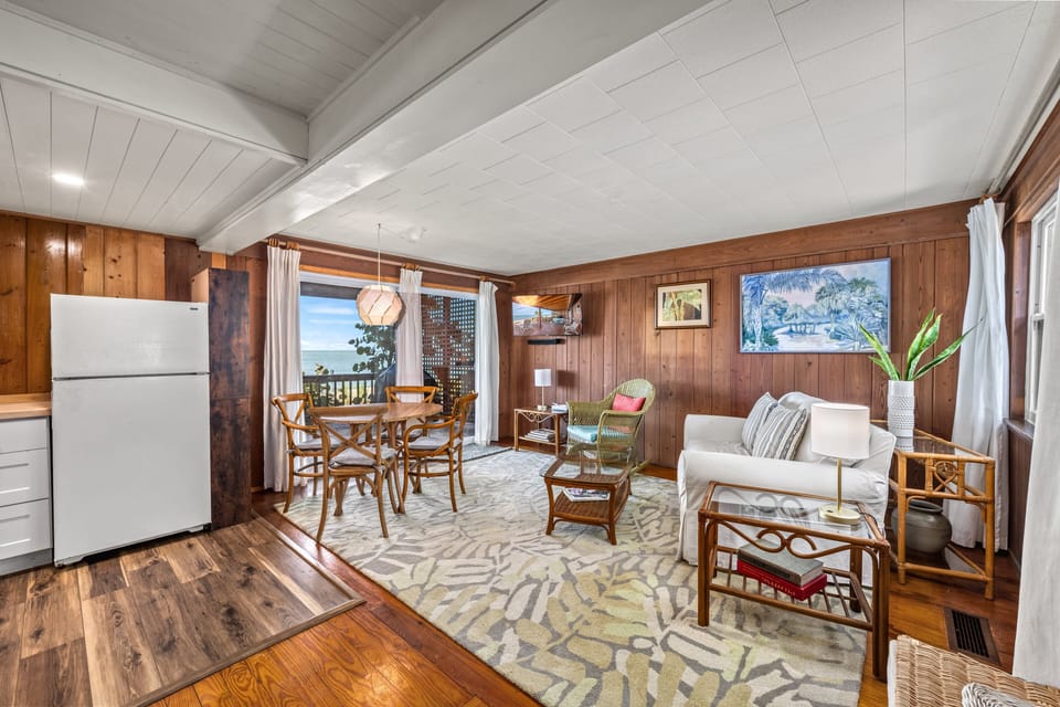 The open living space feels airy and inviting, with comfortable seating and a dining table bathed in sunlight.