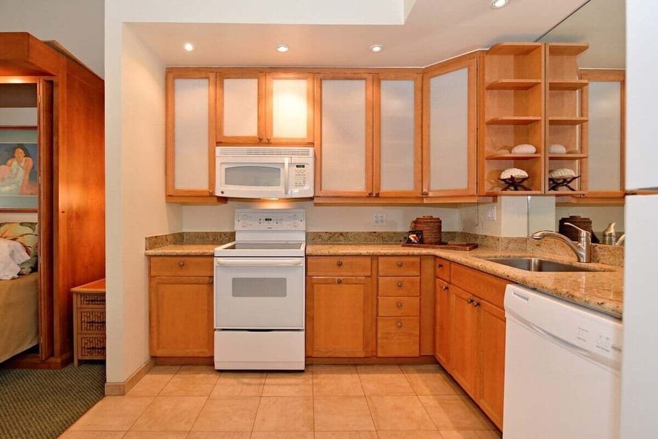 Prepare meals with ease in a clean, organized kitchen featuring granite countertops, wood cabinetry, and full-size appliances.