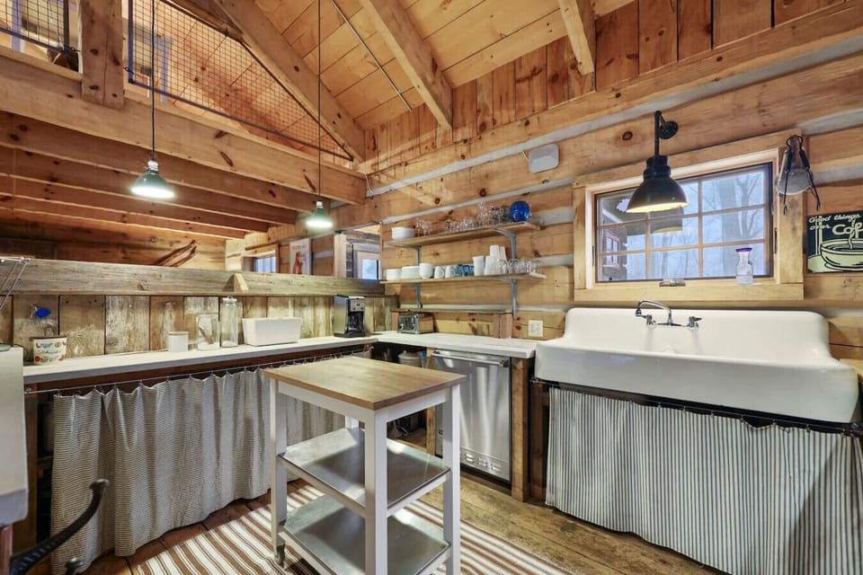 A wide view of the kitchen showcasing the farmhouse sink, open shelving, and inviting log-cabin charm.