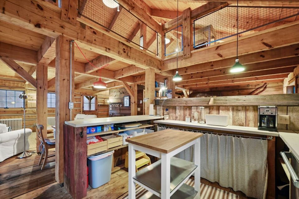 A cozy, fully equipped kitchen with a gas stove, open shelves, and handcrafted wood detailing.