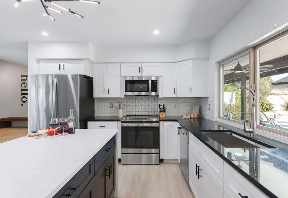 Fully equipped kitchen with stainless steel appliances, a sleek kitchen island with a breakfast bar for casual seating for 2, plus a large dining table for 4.