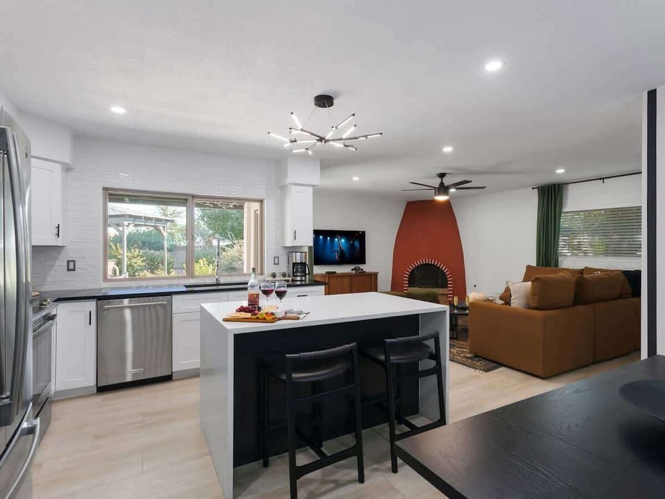 Fully equipped kitchen with stainless steel appliances, a sleek kitchen island with a breakfast bar for casual seating for 2, plus a large dining table for 4.