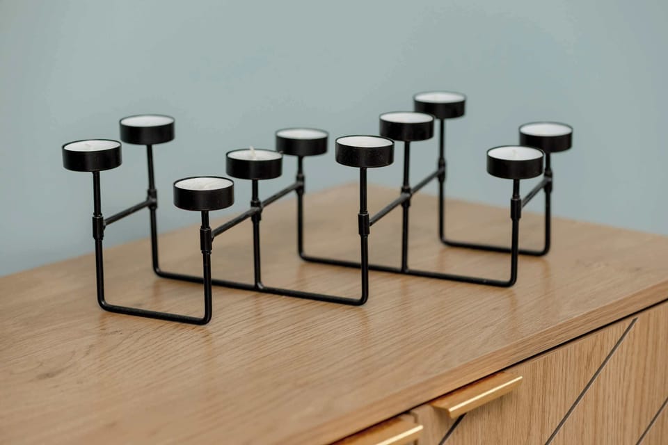 The metal candleholder displayed on the wooden surface brings a modern touch to the interior and adds a pleasing visual accent.