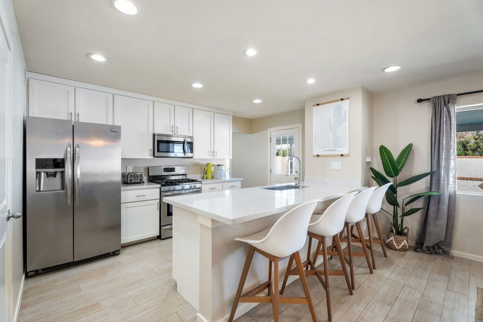 Bright white kitchen with a center island and breakfast bar seating.