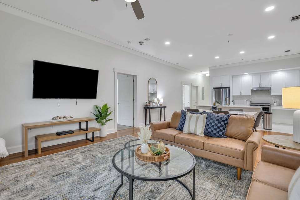 Bright living room featuring modern seating, a smart TV, and a ceiling fan.