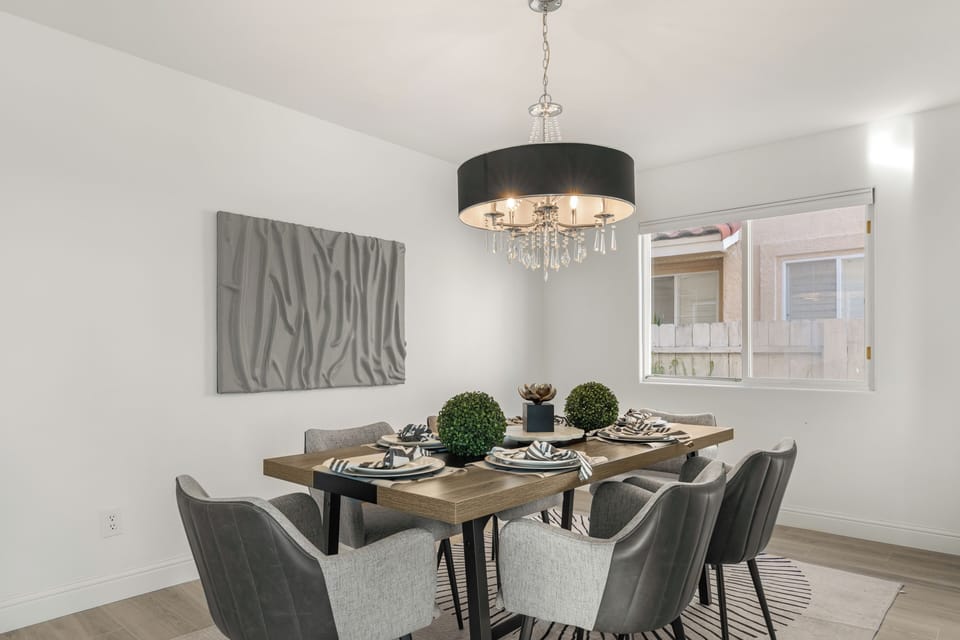 Close-up of the formal dining table set for dinner under a decorative chandelier.