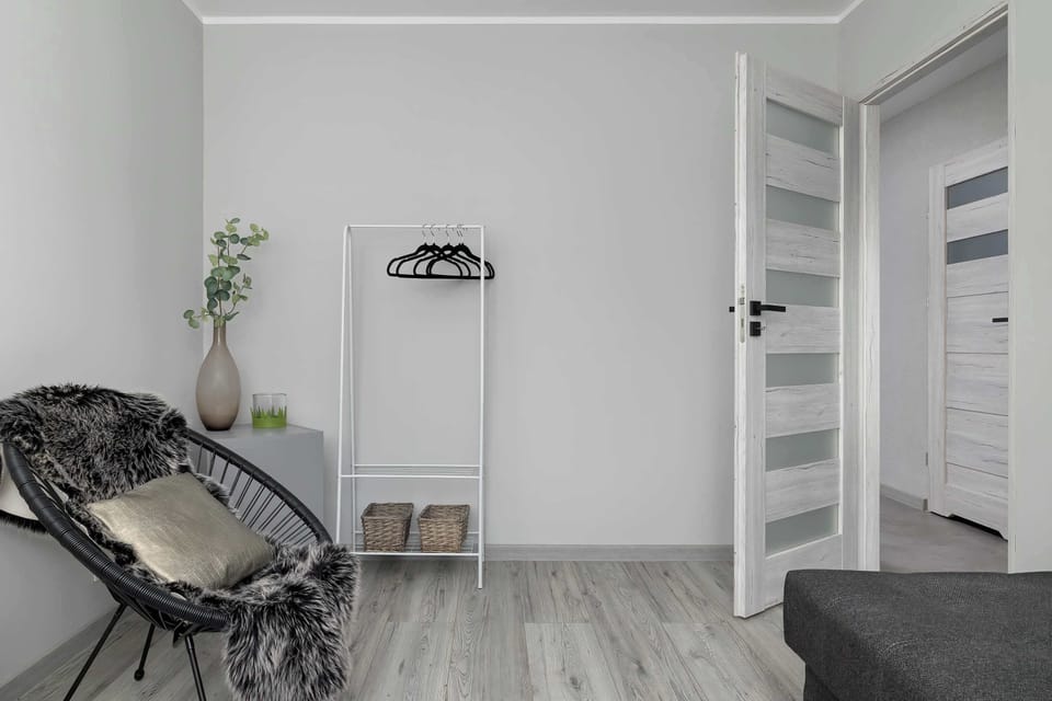 A wider angle of the same seating area, showing more of the layout. Soft gray textures and minimalist décor create a modern vibe. The window brings a bright, open feel.