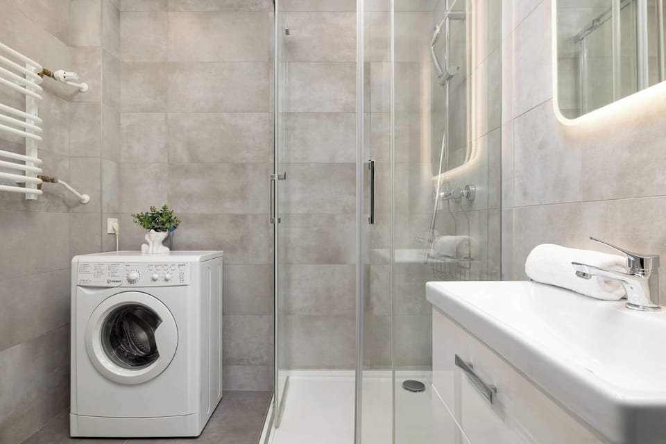 A bathroom with a modern vanity, lit mirror, and glass shower enclosure. Clean surfaces and neutral tiles give the room a spa-like feel. The layout maximizes functionality in a compact area.