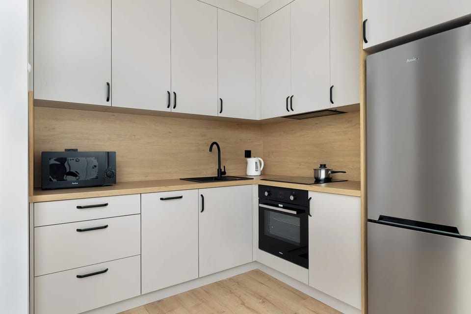 A modern kitchen featuring white cabinets, built-in appliances, and a wooden countertop. The design is functional and elegant.