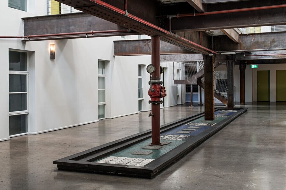 Architecturally striking common foyer showcasing exposed steel beams, industrial detailing and a refined, warehouse-style aesthetic