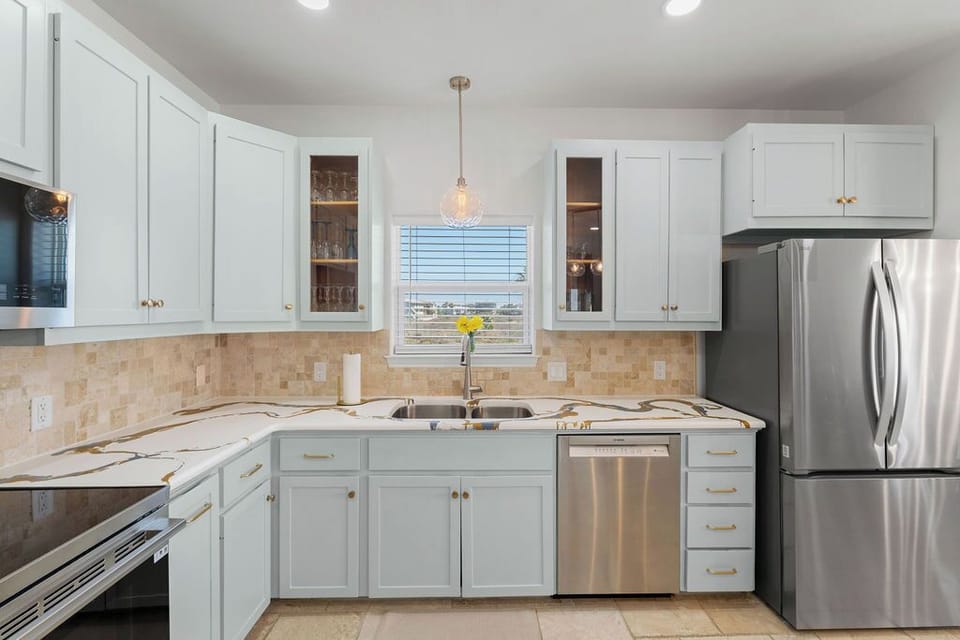 Your fully equipped kitchen features modern stainless steel appliances, elegant white cabinetry, and granite countertops perfect for preparing memorable meals together.