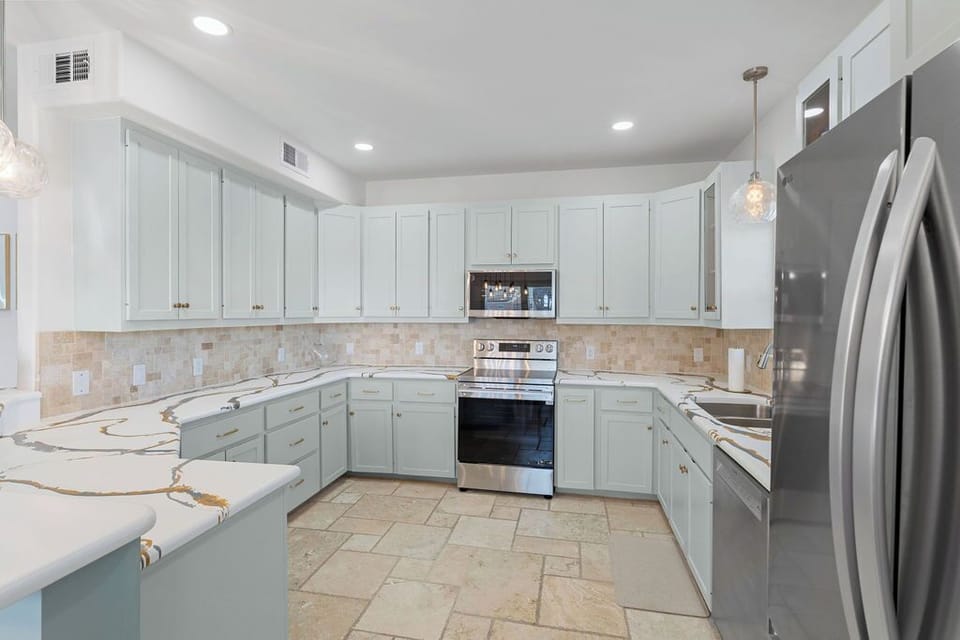 Your spacious modern kitchen features elegant marble countertops, stainless steel appliances, and soft blue cabinetry creating a serene cooking experience.