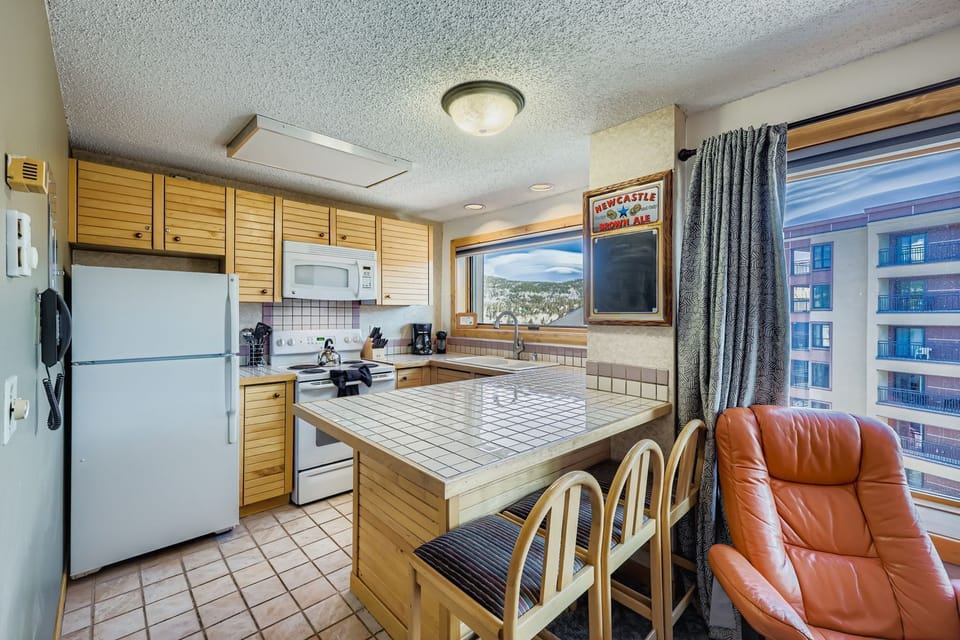 Your fully equipped kitchen features modern appliances and a central island with seating, perfect for preparing meals and enjoying casual dining with city views.