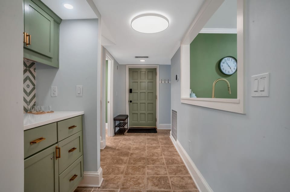 Your stylish kitchen features sage green cabinets, white quartz counters, and warm brass accents creating a fresh, welcoming space for cooking.