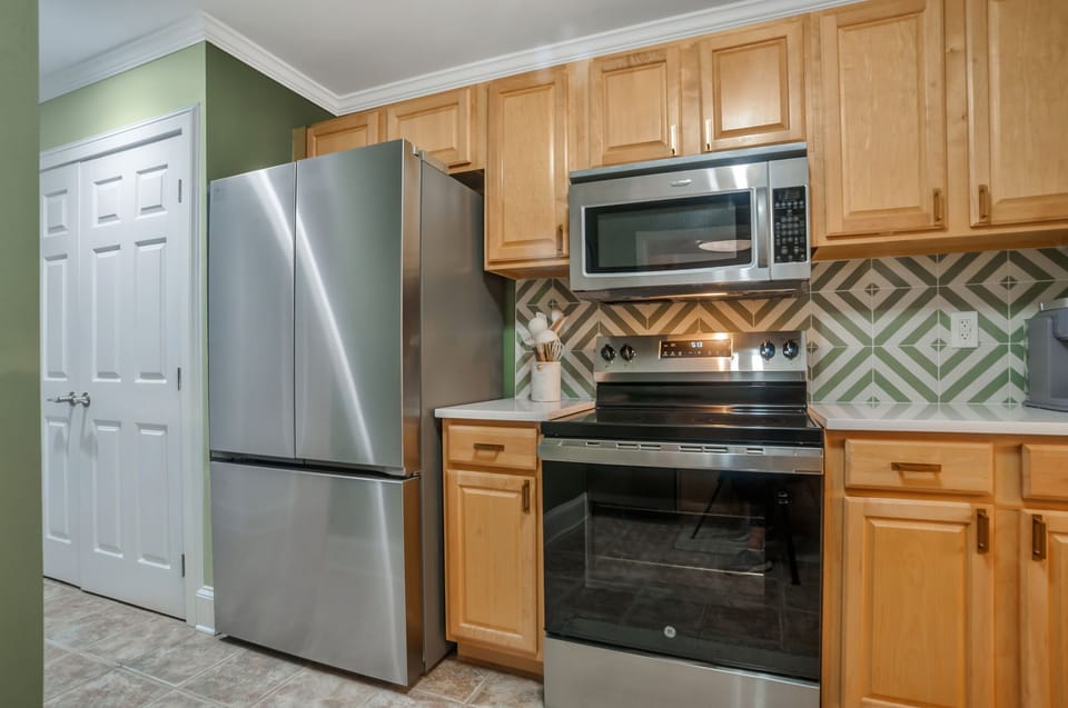 Cook memorable meals in your fully-equipped kitchen featuring stainless steel appliances and stylish green geometric tile backsplash.