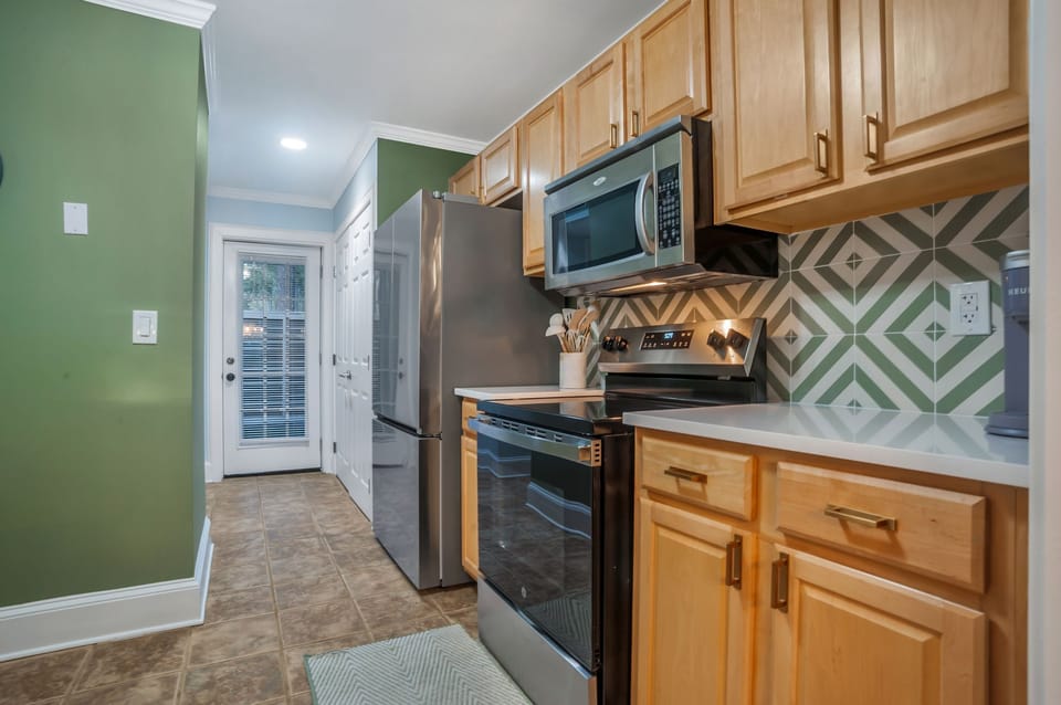 Your fully equipped kitchen features warm wood cabinets, stylish geometric backsplash, and all the appliances you need for preparing meals during your stay.