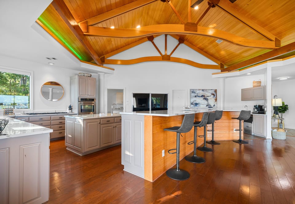 Chef's kitchen with vaulted ceilings, island seating, and open flow.
