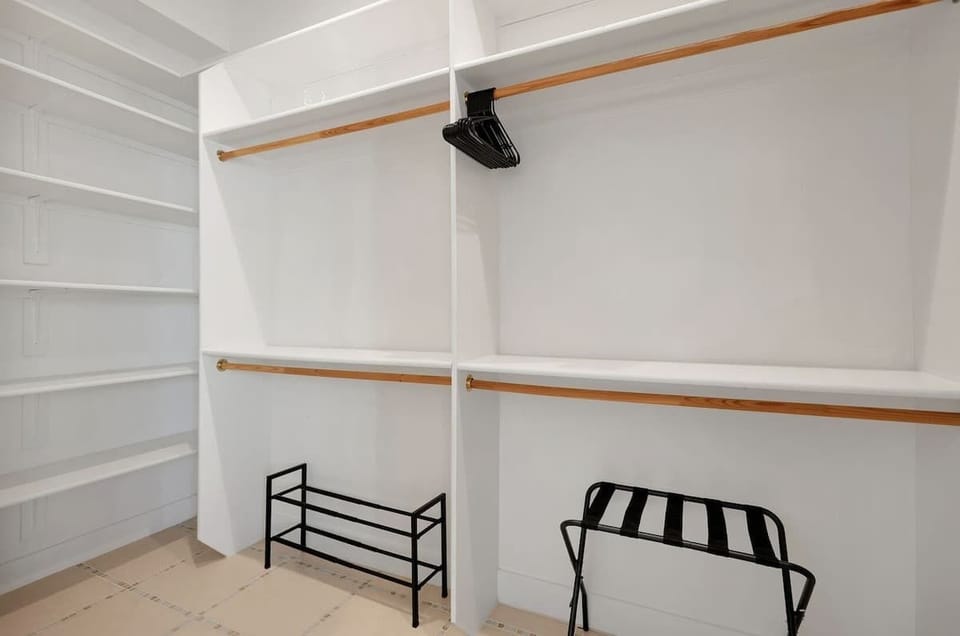 The primary bedroom offers a stylish retreat with a king bed, modern décor, a walk-in closet, and direct access to an en-suite bathroom.