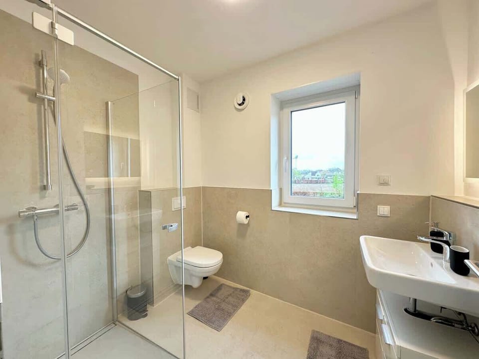 Tageslichtbad mit bodentiefer Dusche, Toilette, Waschtrockner Föhn, Seife, Shampoo, Toilettenpapier und frischen Handtüchern.
Um das Fenster abzudunkeln, gibt es elektrische Rollläden.