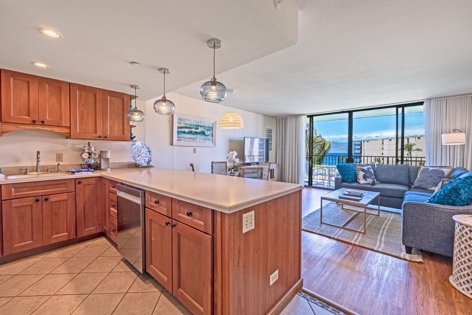 Experience a well-appointed kitchen with rich wood cabinetry, polished countertops, and an open layout that flows effortlessly into the sunlit living room.