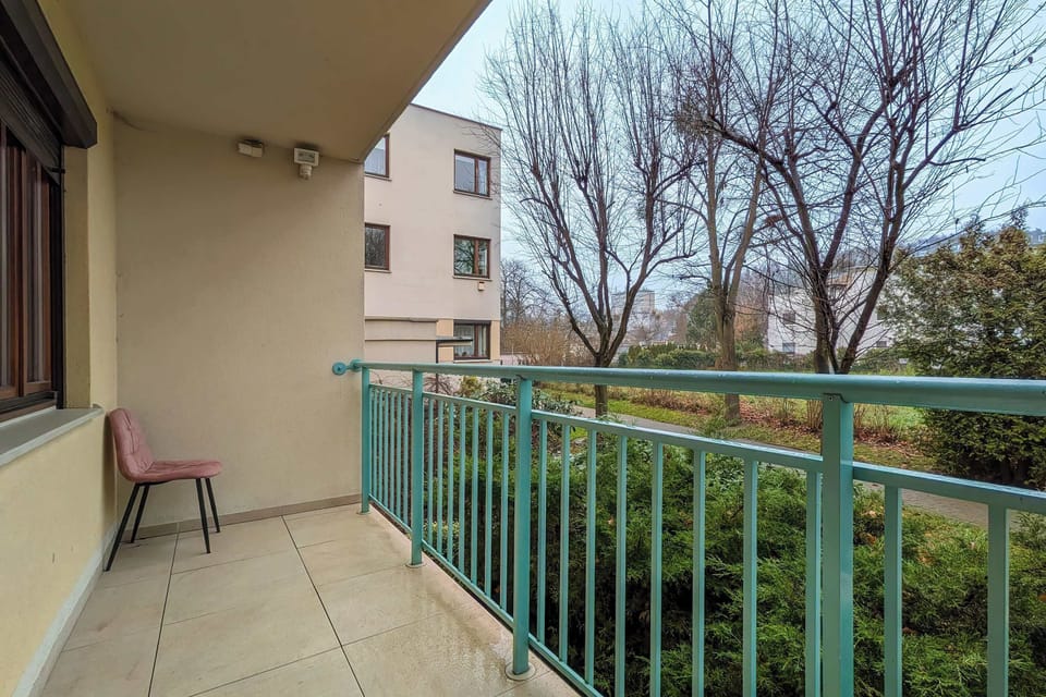 A balcony with a small table and chair, overlooking a quiet garden area. Ideal for enjoying fresh air and outdoor views.