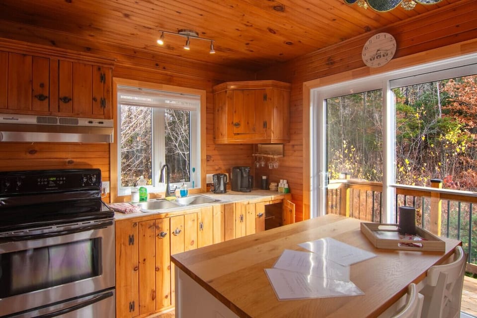 A functional and well-designed kitchen, featuring a central island, a coffee machine, a toaster, and direct access to the outside. Perfect for preparing family meals.