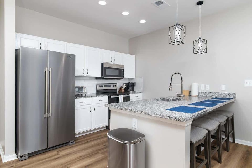Brightly stocked kitchen with all major appliances, a dishwasher, and a large island with seating for four.