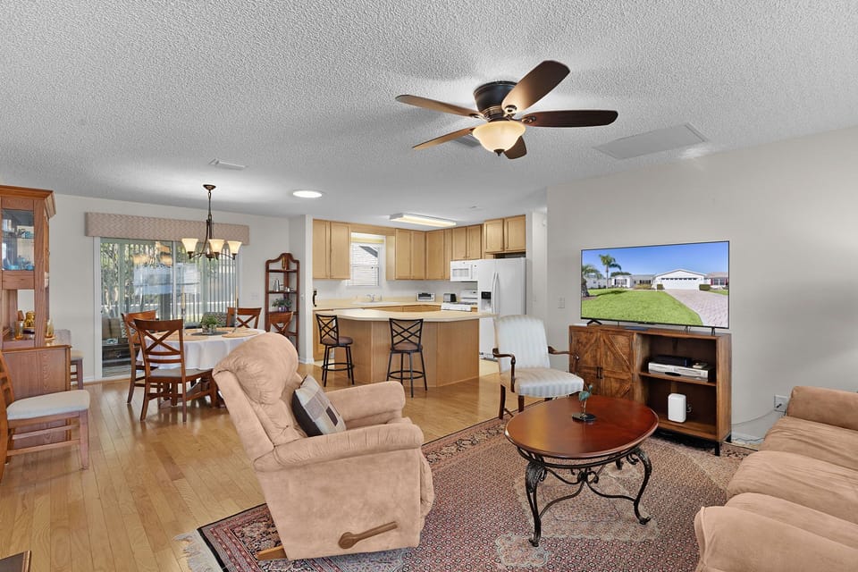 Relax in your spacious open-plan living area where warm wood tones meet comfortable seating, perfect for family gatherings.