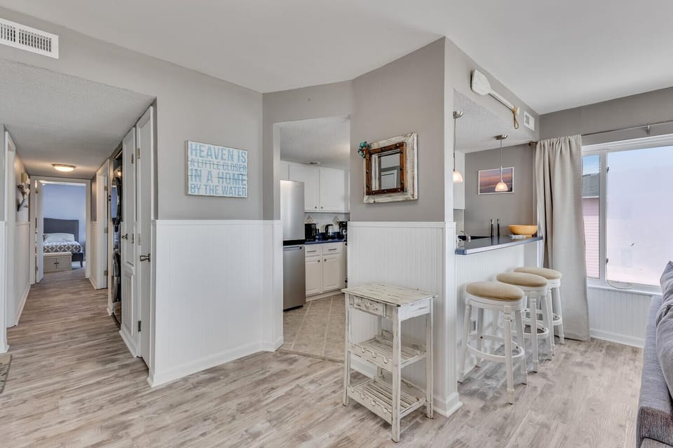 Your bright kitchen features white cabinets, a breakfast bar with stools, and charming coastal decor that makes cooking feel like a breeze.