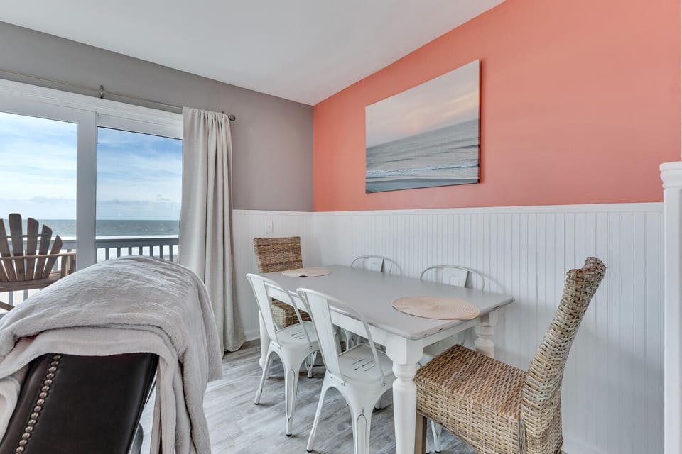 Enjoy meals with stunning ocean views from your coastal dining nook, featuring cheerful coral walls and comfortable seating.